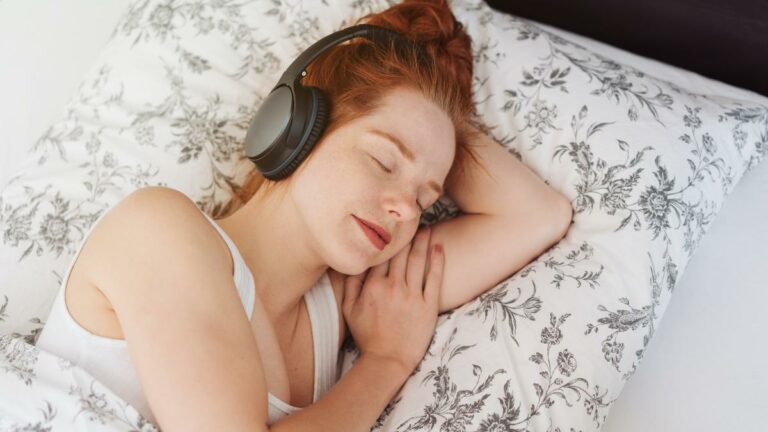 Mulher dormindo usando fones de ouvido, mostrando a utilização de ruídos para sono.