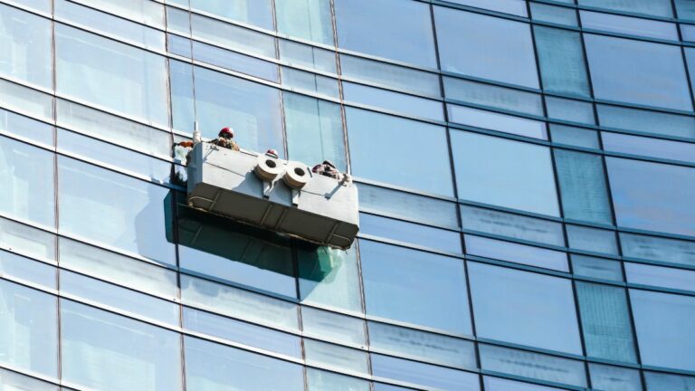 vidraceiros realizando a manutenção em vidros de um prédio.