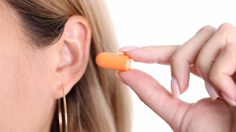 mulher segurando um protetor auricular próximo a orelha